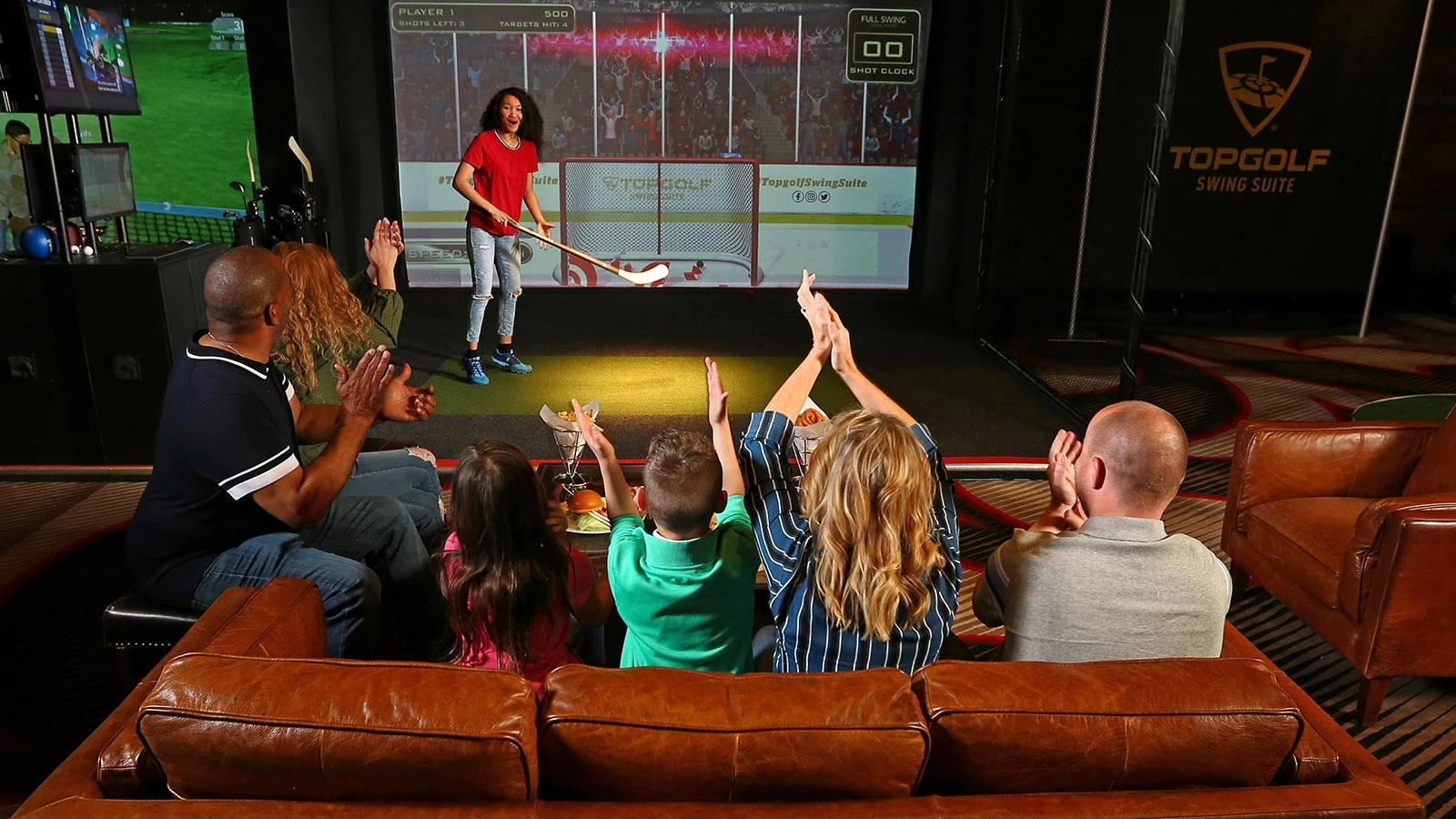 Family playing hockey at a TopGolf simulator